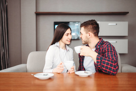 年轻幸福爱夫妇在家喝咖啡在木桌
