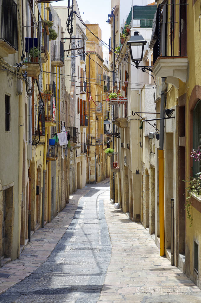 在晴朗的晴天, 旧欧洲城镇冷清的街道.加泰罗尼亚旧城区的明亮城墙