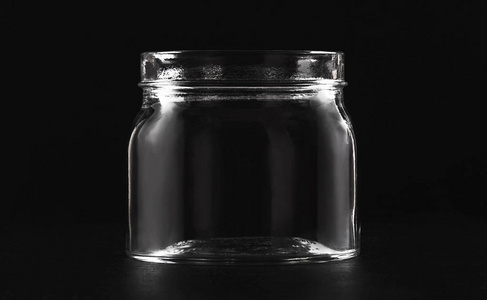 黑色背景上的透明玻璃空罐子照片