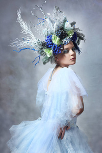 冬仙女或雪皇后妇女在浅蓝色薄纱礼服户外佩戴花卉皇冠