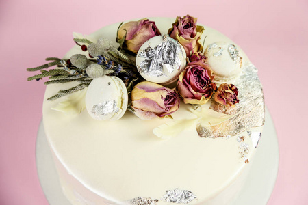 用 macaron 和玫瑰装饰的慕斯蛋糕。粉红色背景