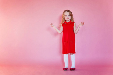 小可爱的甜美微笑的女孩在红色礼服站在粉红色五颜六色的粉彩新潮现代时尚的固定背景