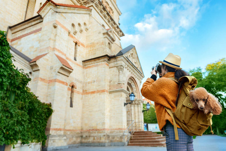 妇女旅行者与狗在背包制作照片与相机在旅行时