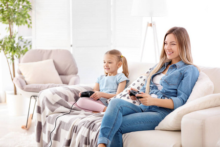 在家里和女儿玩电子游戏的年轻女子