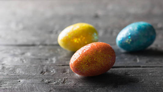 三五颜六色的鸡蛋在一个黑暗的木桌上。复活节餐桌的装饰