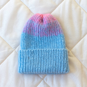 针织的帽子用蓝色和粉红色的羊毛的梯度手工转动