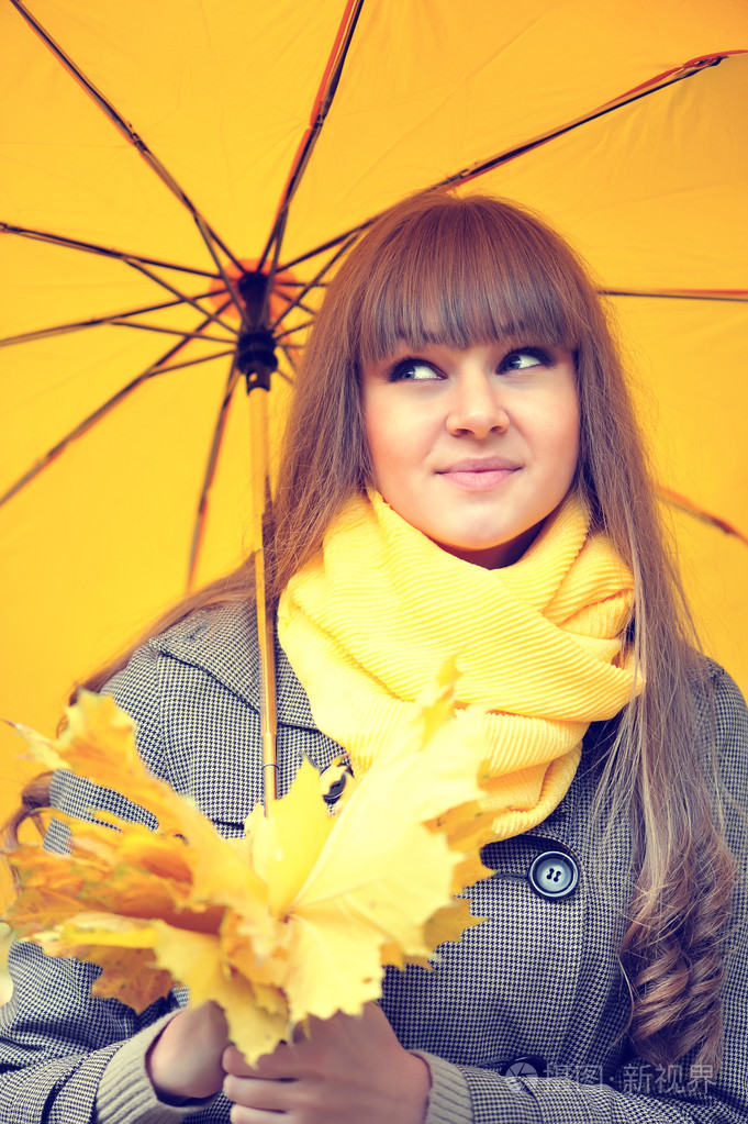 美丽的年轻女子，与一把黄色的伞