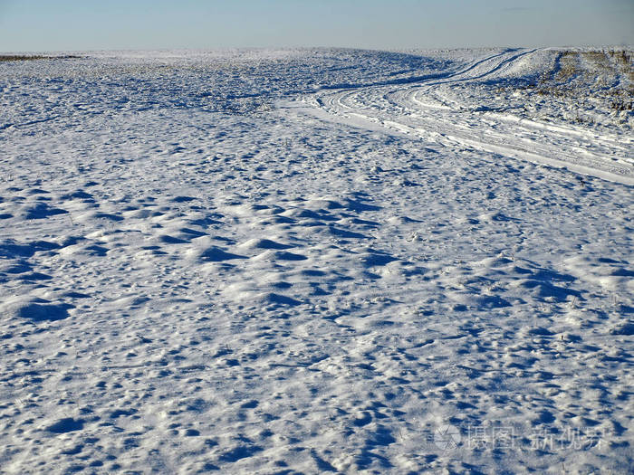 雪覆盖的草地与汽车在冬季的痕迹风景如画的看法