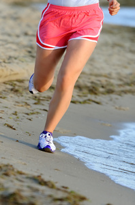 在海滩上运行赛跑者的双的腿