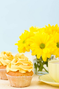 配有黄色奶油装饰的蛋糕牛奶咖啡和小酒杯杯中的黄色菊花花束
