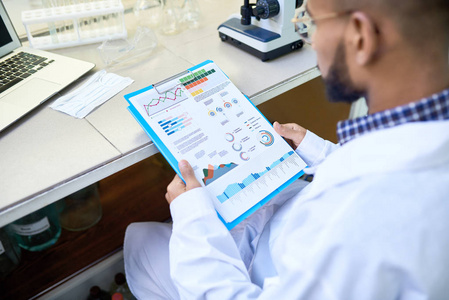 在实验室进行医学研究时, 年轻的中东科学家的肩膀肖像看数据图表