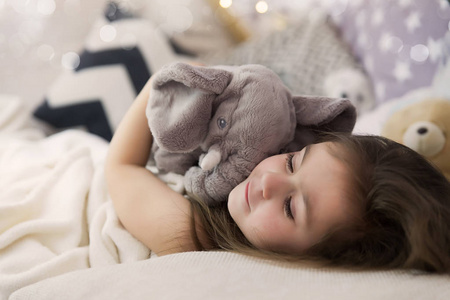 可爱的快乐的小女孩睡觉, 做梦在床上拥抱她的玩具.