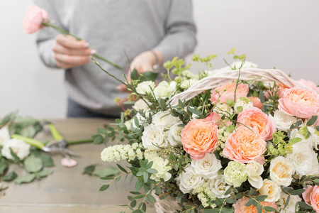 特写手女花店。花卉车间妇女制作一个美丽的花朵组合在一个柳条篮子花束。植物理念