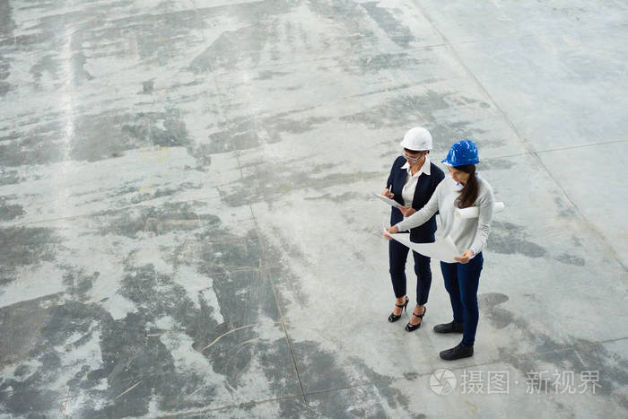 两名女工程师高角度看现代工厂车间 hardhats 检测平面图