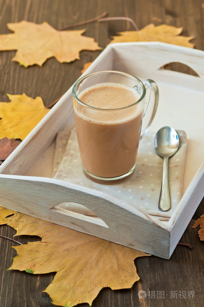 杯咖啡加牛奶木背景与秋天叶子