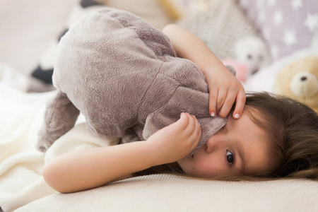 可爱的快乐的小女孩睡觉, 做梦在床上拥抱她的玩具.