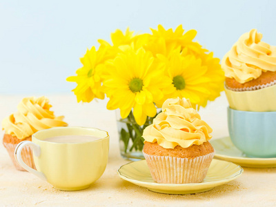 小玻璃杯配以黄色奶油装饰的蛋糕, 牛奶咖啡和黄色菊花花束