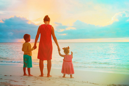 母亲和两个孩子在沙滩上行走