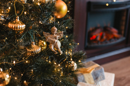 可爱的玩具金黄天使挂在装饰圣诞树与礼物在温馨的家