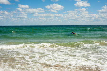 夏天, 女孩学会在海里骑冲浪板。骑在冲浪板上的海浪在一个美丽的地方。海滩上的冲浪学校
