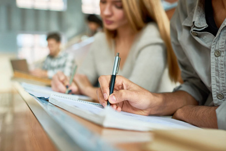 在大学期间, 学生在课堂上坐在办公桌前的笔记, 专注于手写, 复制空间