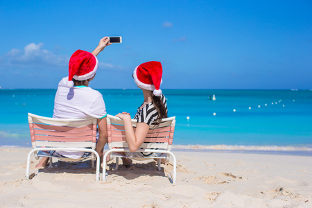 幸福的夫妇在加勒比海滩穿圣诞老人的帽子