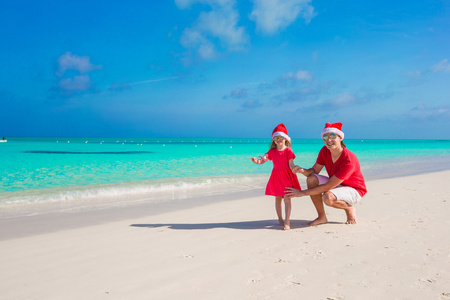 小女孩，在圣诞老人的帽子在异国海滩的快乐老爸