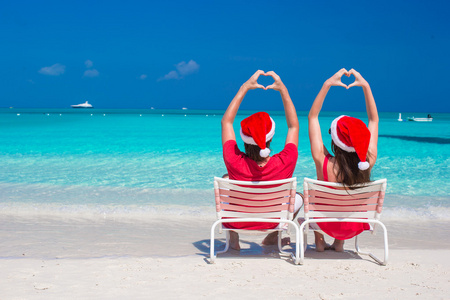 快乐浪漫的情侣在海滩使心的红色圣诞帽。