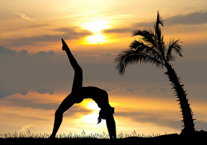 日落时棕榈树中的瑜伽