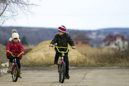 两个快乐的孩子男孩和女孩在户外骑自行车冷