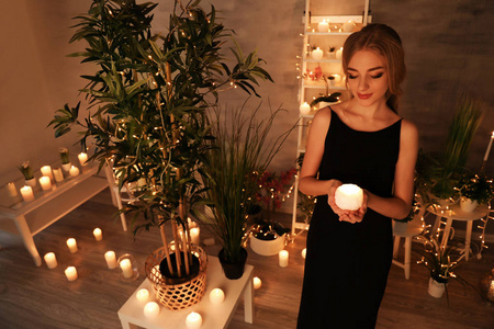 美丽的年轻女子在家里拿着蜡烛
