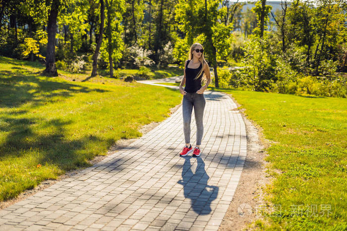 年轻美丽的妇女与眼镜散步在公园在白天