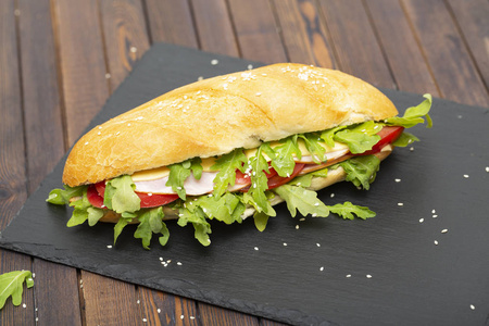 长方形三明治配火腿西红柿芝士和芝麻菜生菜。美味的早餐或小吃。特写