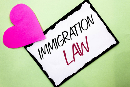 手写文字书写移民法。概念意味着移民驱逐出境规则在纯背景上写在白色粘纸条上的国家条例与它旁边的心脏
