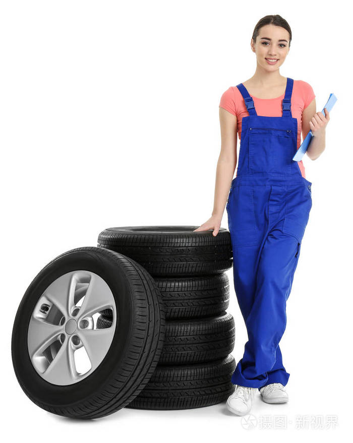 女性技工在制服与汽车轮胎和剪贴板在白色背景下