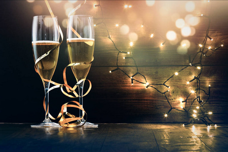两个香槟眼镜, 带丝带反对节日彩灯和烟花新年庆典
