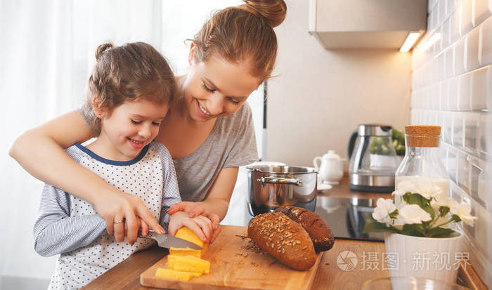 准备一份家庭早餐。母亲和孩子的女儿早上切面包和奶酪