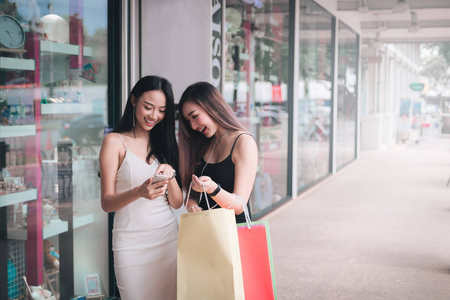 两个 beatyful 的女人在购物中心使用智能手机