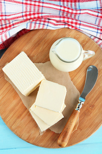 新鲜的黄油切菜板上一壶牛奶，彩色木背景上的