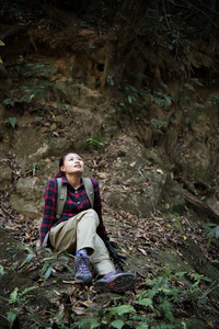 女徒步旅行者在森林里休息坐在附近瀑布享受大自然