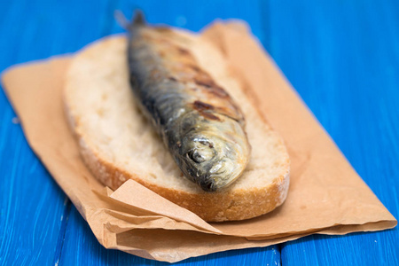 griiled 沙丁鱼在面包上蓝色木质背景