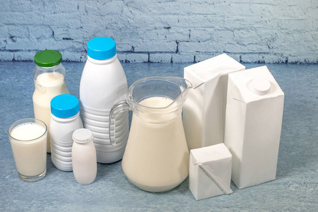 牛奶砖混合牛奶瓶和包装在蓝色砖背景隔离照片