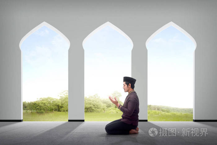 亚洲男性穆斯林在清真寺内向上帝祈祷的侧面观点