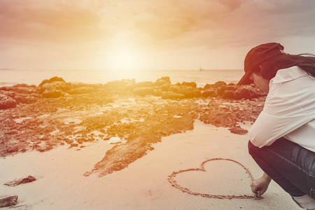 爱浪漫的少年在夏日沙滩上画下落日的心