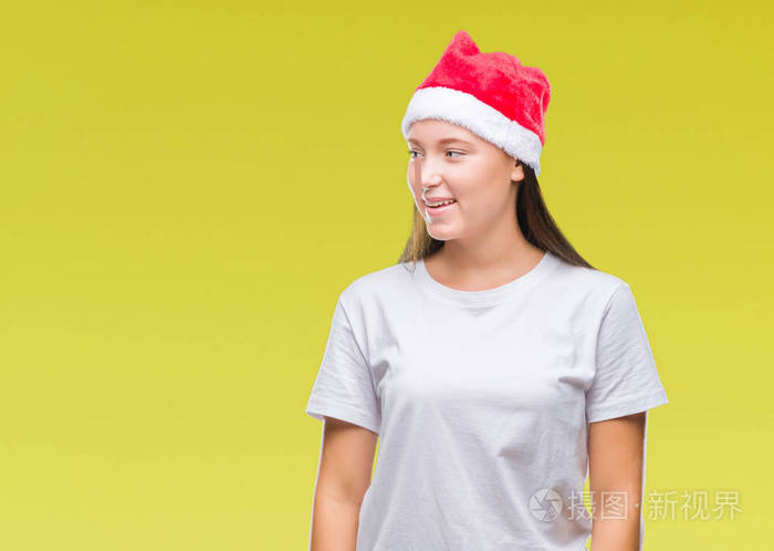 的高加索妇女戴着圣诞帽在孤立的背景看着一边面带微笑, 自然的表情