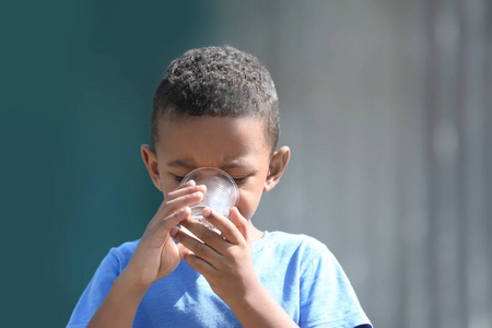 可爱的非洲裔美国男孩饮用水从塑料杯, 户外