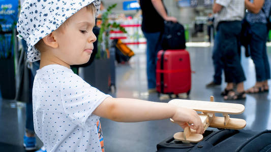 玩玩具飞机和大手提箱的小男孩的肖像