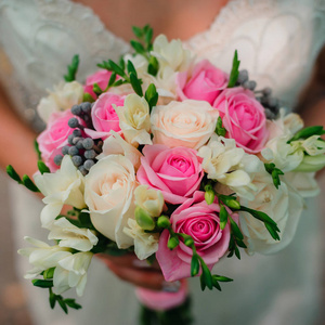 婚礼美丽的花束与微妙的白色和粉红色的玫瑰在手中