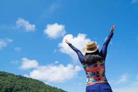 旅行者女人与多彩泳衣举起手臂向天空