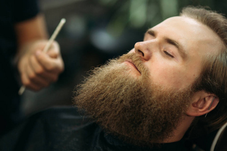 胡子男子得到一个专业理发师理发, 使用梳子和修剪剪刀。具有浅景深的特写视图